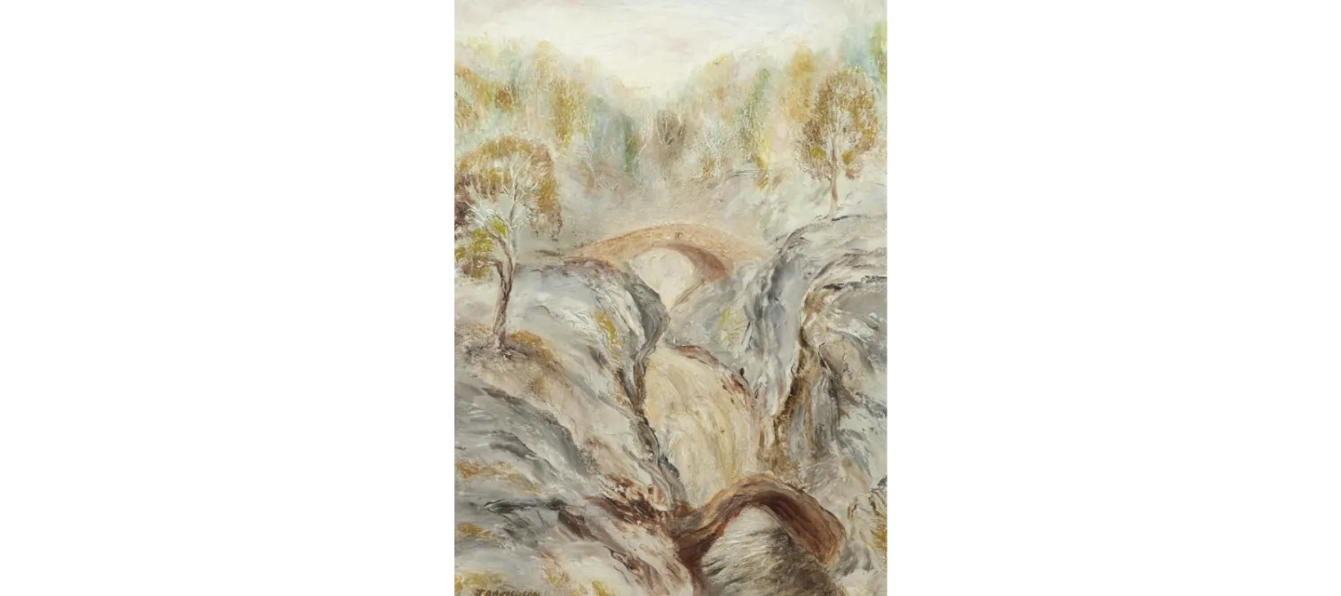 a landscape showing rough rocks, divided by a stream and connected with a bridge, a forest in the background underneath a blue sky.