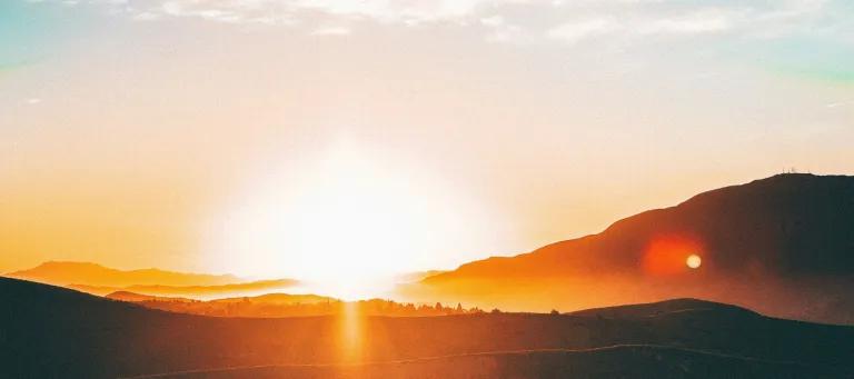 a sunset over some hills