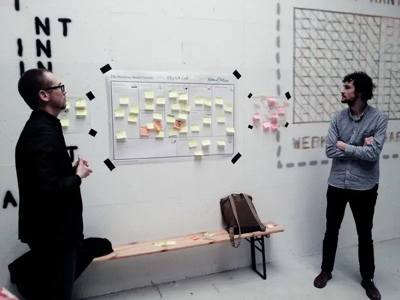 two people looking at a board with lots of post-it-notes on