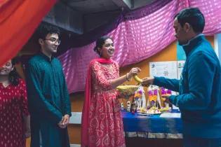 2 people in traditional Hindu dress and one person receiving a banana 