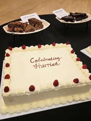 A large white cake with raspberries saying, "celebrating Harriet"