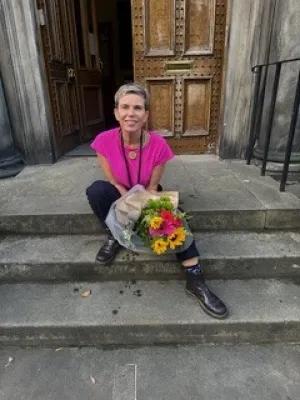 Janine sitting on stone steps holding flowers