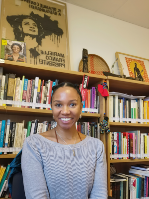 a woman sitting in front of a bookshelf smiling 