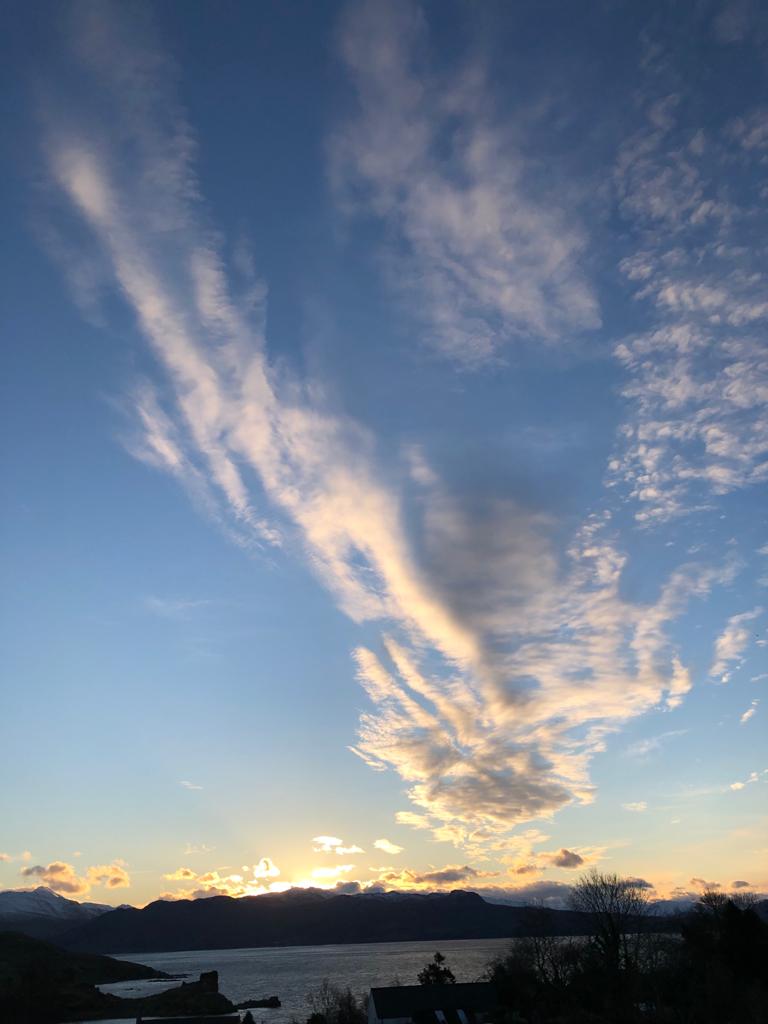 Photograph of dawn over a body of water, with hills in the background. 