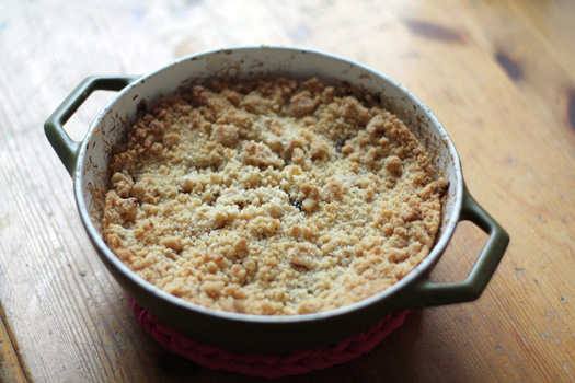 Photograph of an apple crumble in a dish on a table.