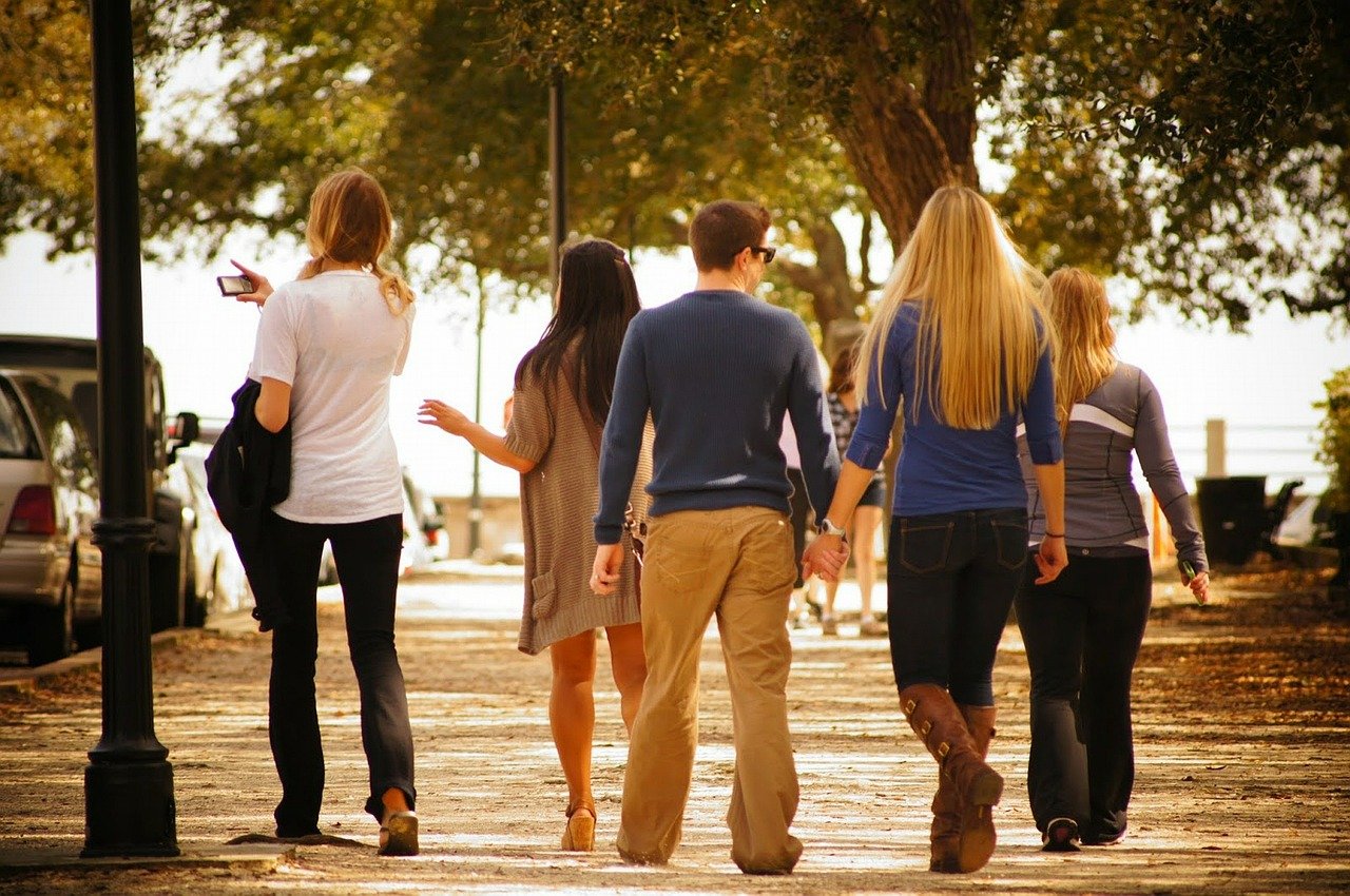 Photograph of friends walking outside together. There is a group of 5 people walking along a path together.