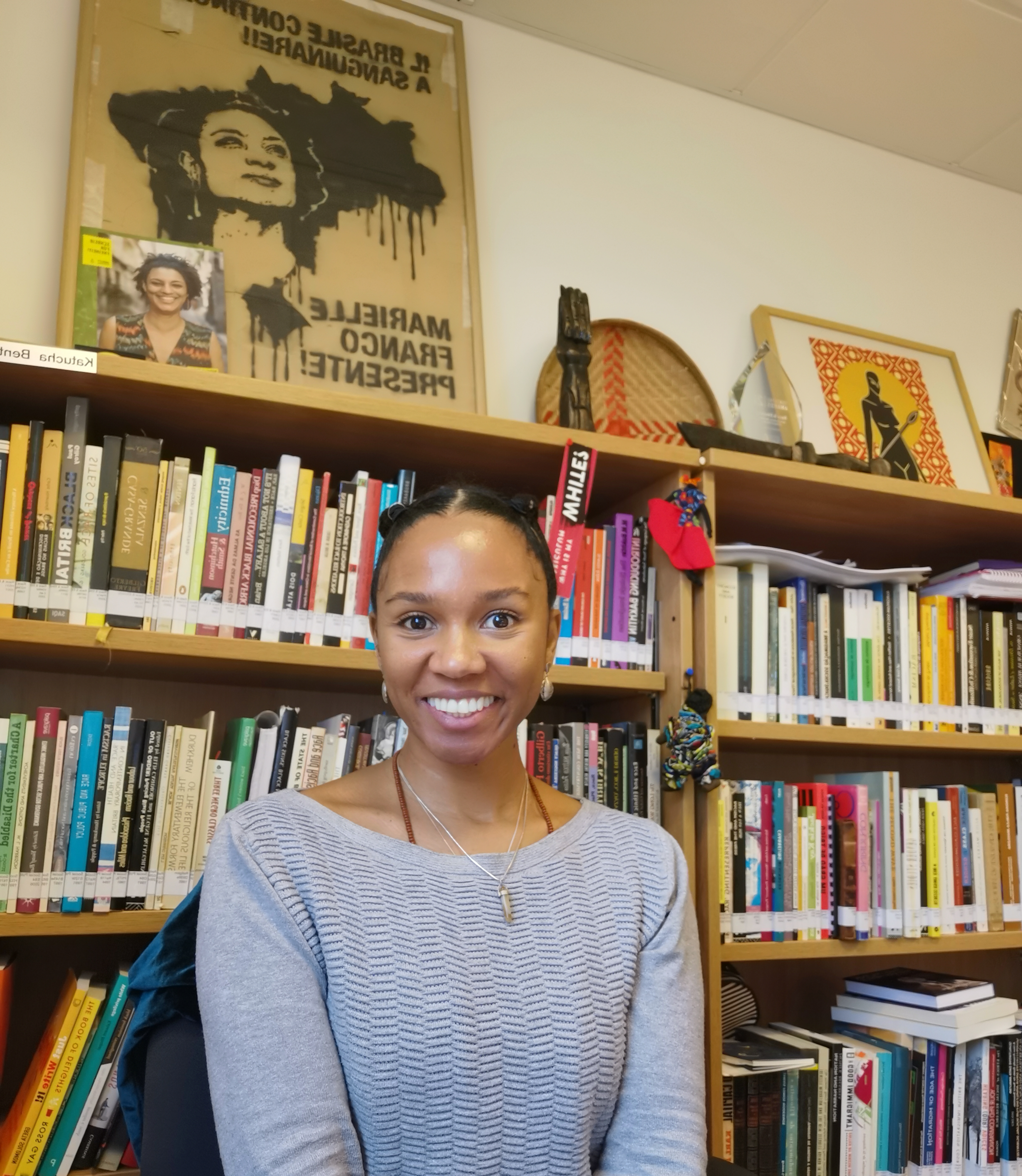 a woman sitting in front of a bookshelf smiling 