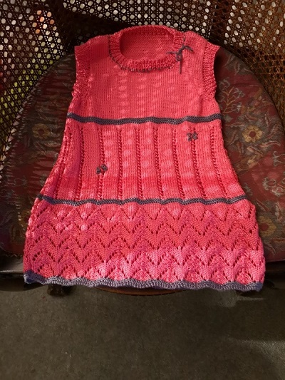 Photograph of a pink knitted dress lying on a chair.