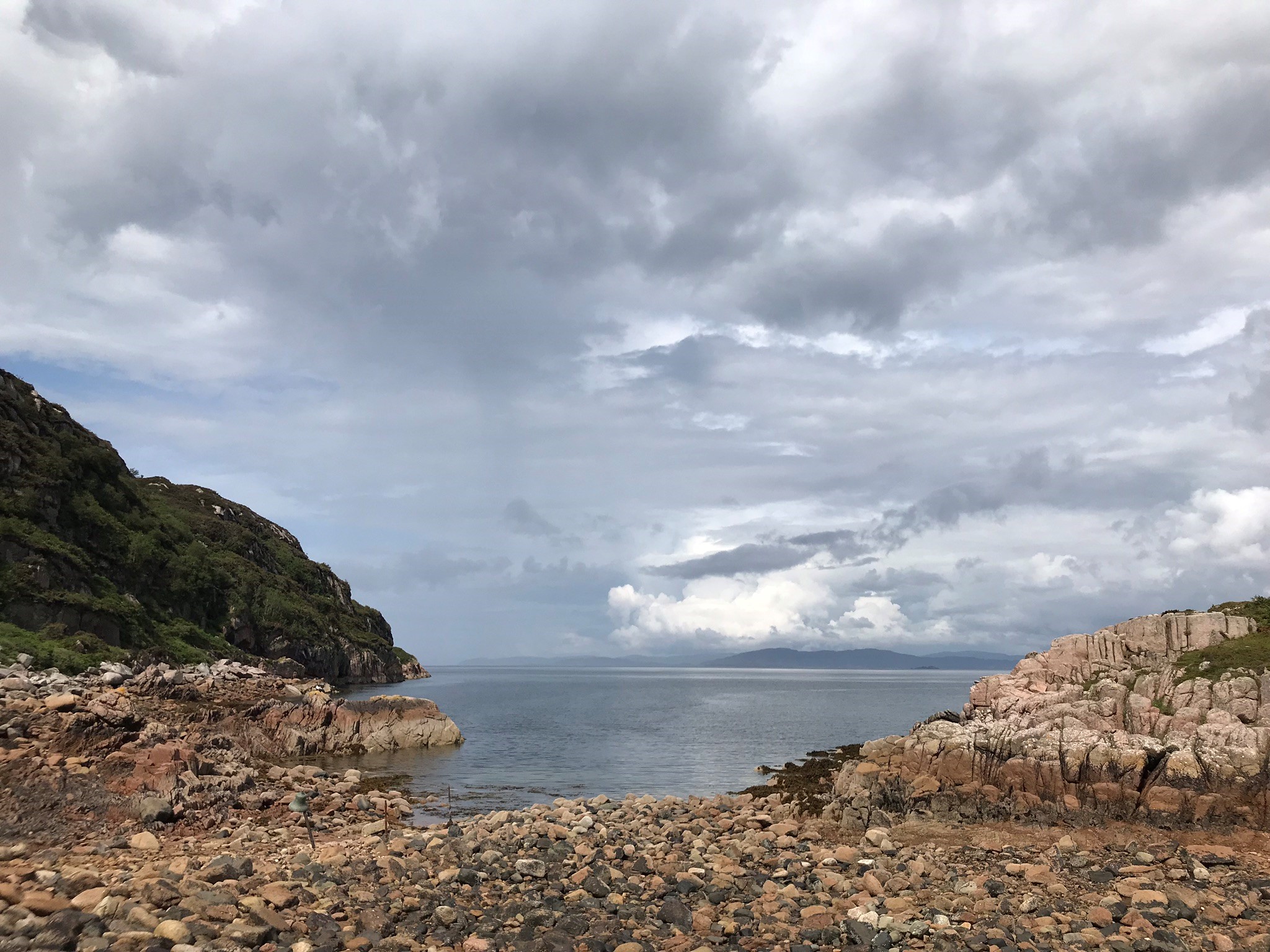 Photograph taken from a beach on the Isle of Mull. There are small stones on the beach looking out to sea