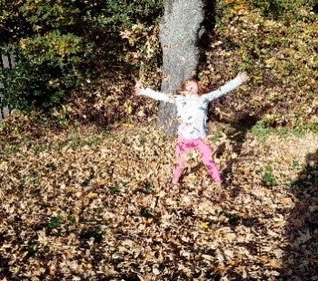 someone playing in a pile of leaves