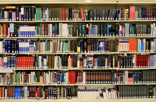 Photograph of book shelves in a library filled with lots of different coloured books 