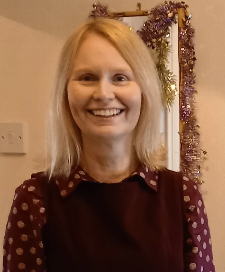 Lynne Standing in front of the some tinsel smiling at the camera 