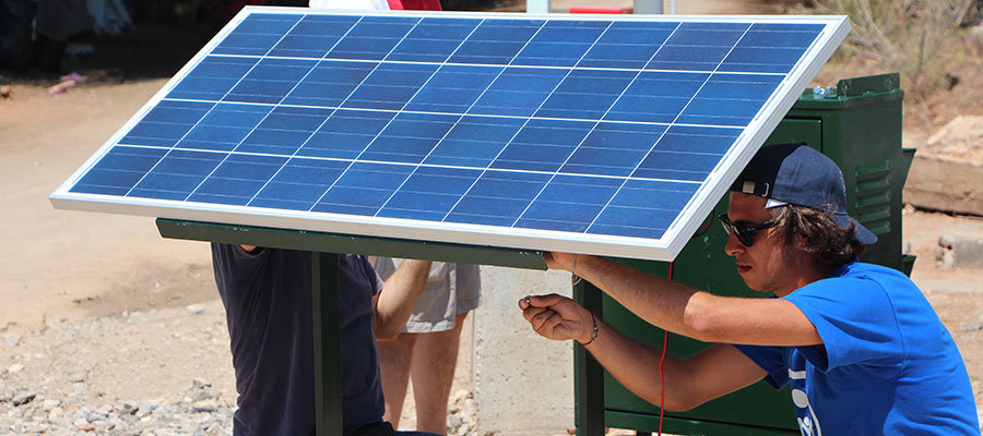 Photograph of people working on a solar panel. 