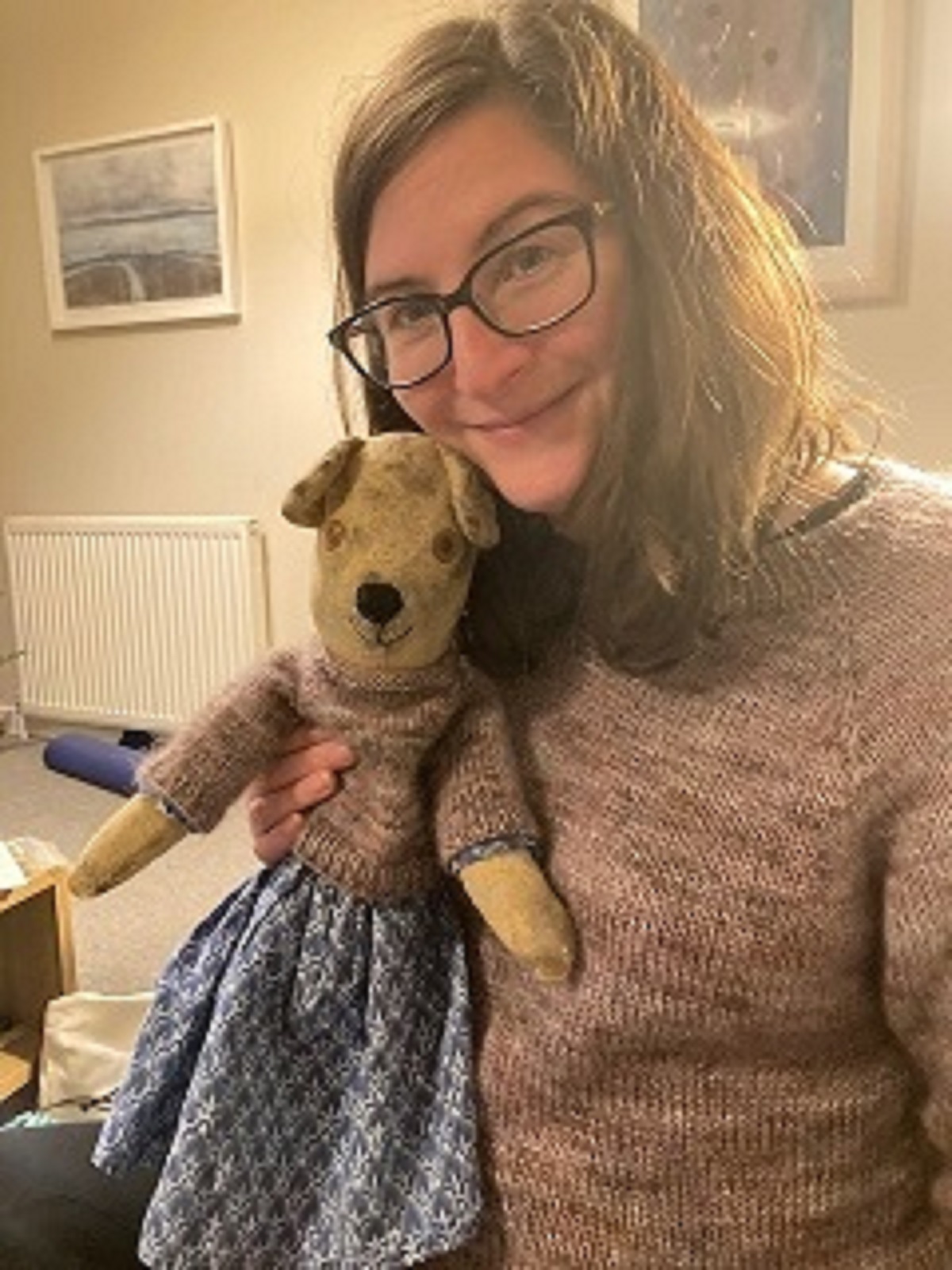 Photograph of Victoria holding teddy, both are wearing matching brown jumpers. 